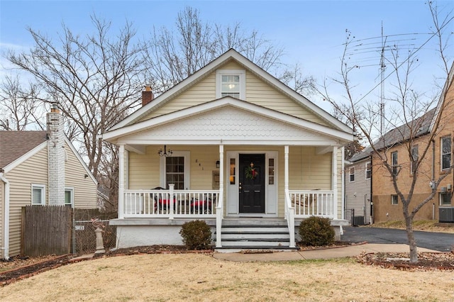 bungalow-style home with cooling unit, a front lawn, and covered porch