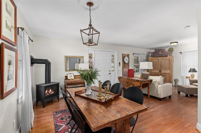 dining space with light hardwood / wood-style floors and a wood stove