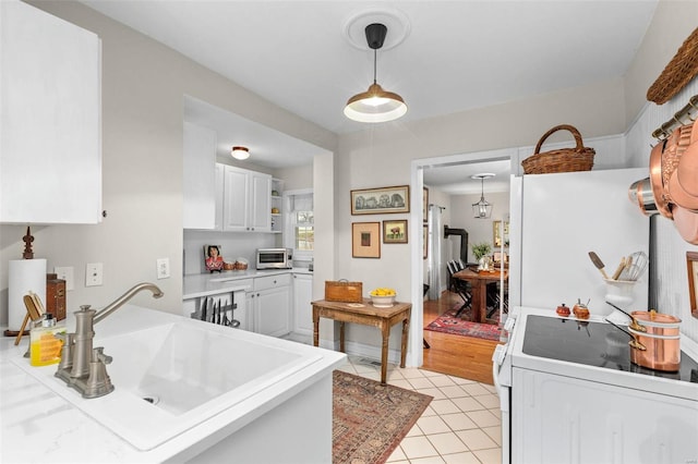 kitchen featuring pendant lighting, sink, white appliances, light tile patterned floors, and white cabinetry