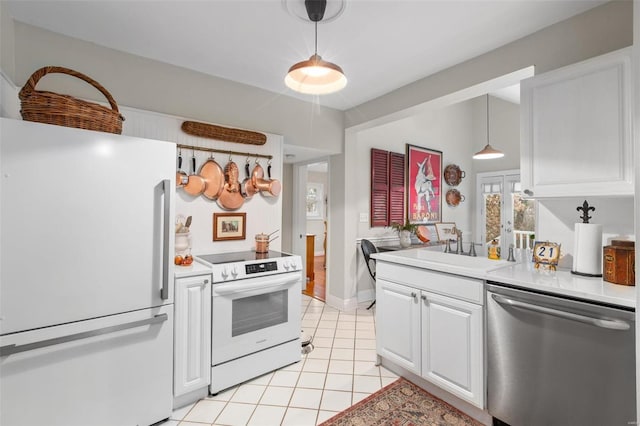 kitchen featuring light tile patterned flooring, decorative light fixtures, white cabinetry, sink, and white appliances