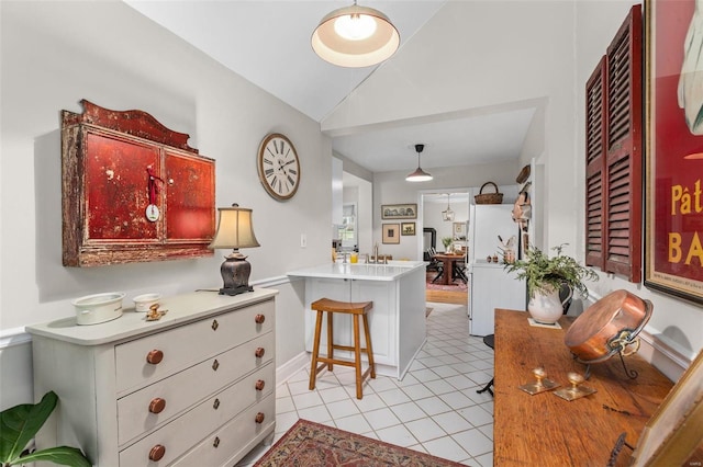 kitchen with lofted ceiling, light tile patterned floors, sink, a kitchen bar, and kitchen peninsula