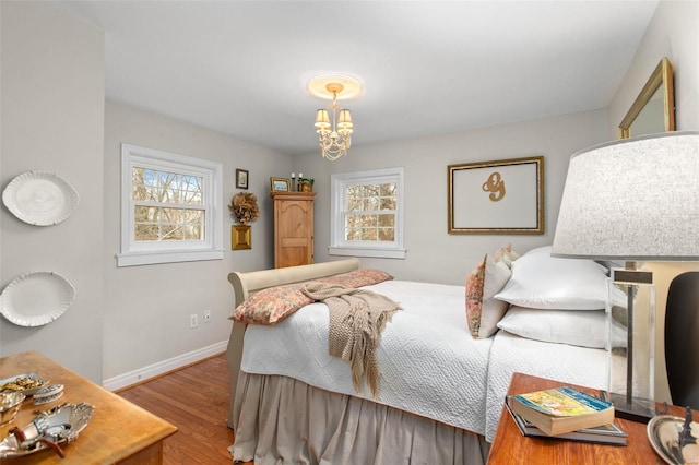 bedroom featuring an inviting chandelier, multiple windows, and light wood-type flooring