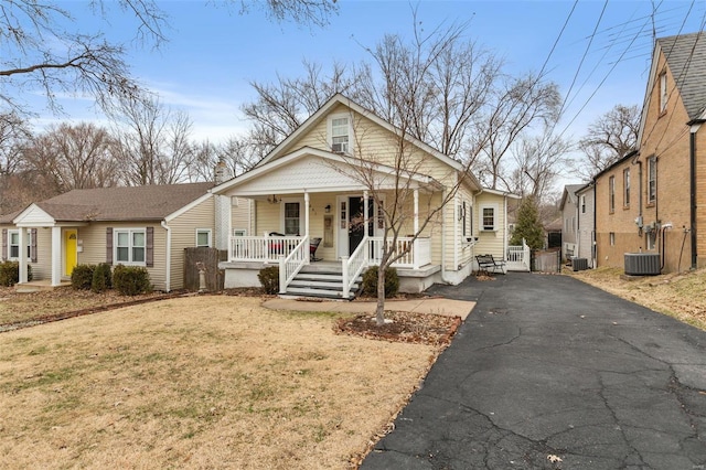 bungalow-style house featuring cooling unit, covered porch, and a front lawn