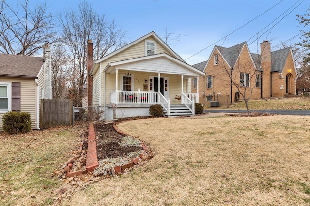 view of front of home with central AC unit, a front yard, and a porch