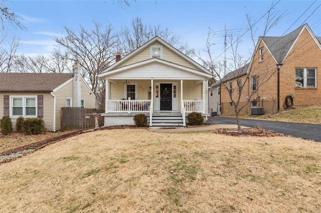 view of front of home featuring a porch, a front yard, and central AC unit