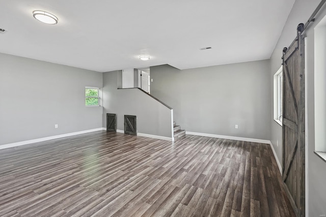 unfurnished living room featuring wood-type flooring and a barn door