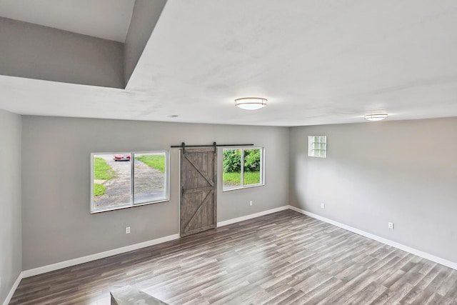 spare room with wood-type flooring and a barn door