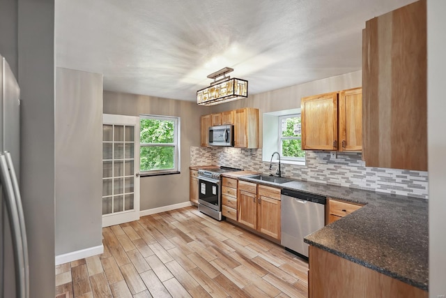 kitchen featuring decorative light fixtures, sink, decorative backsplash, light hardwood / wood-style floors, and stainless steel appliances