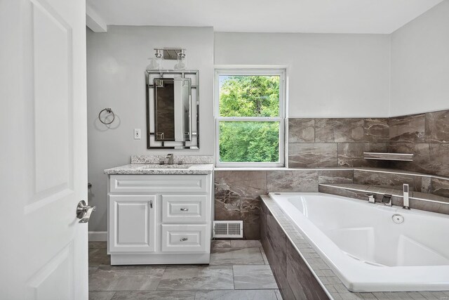 bathroom with vanity and tiled bath