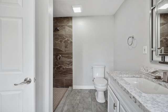 bathroom featuring vanity, toilet, and a tile shower