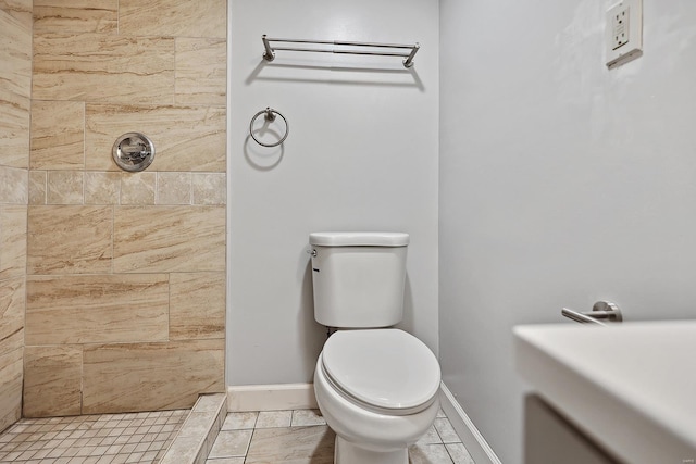 bathroom featuring a tile shower and toilet