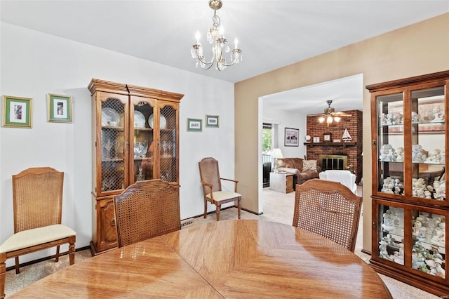 dining room featuring light carpet, a brick fireplace, and ceiling fan with notable chandelier