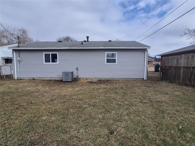 rear view of house featuring central AC and a lawn