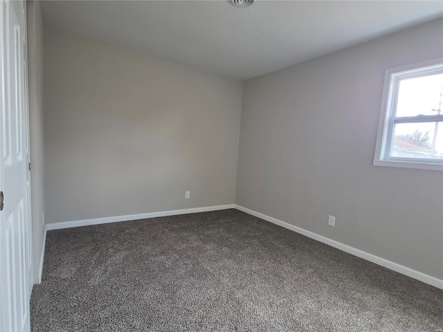 spare room featuring dark colored carpet