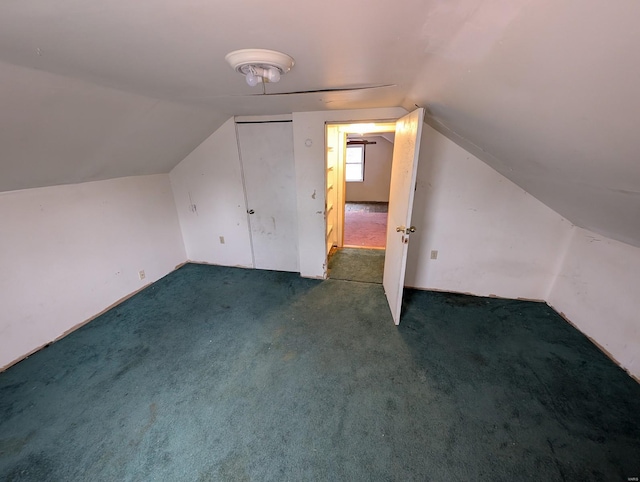 additional living space featuring dark colored carpet and lofted ceiling