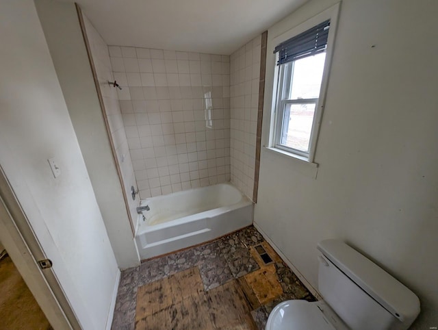 bathroom featuring toilet and tiled shower / bath