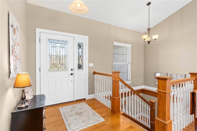 entryway with a notable chandelier, a wealth of natural light, and light wood-type flooring