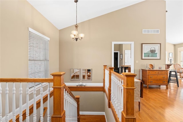 staircase with high vaulted ceiling, hardwood / wood-style floors, and a notable chandelier