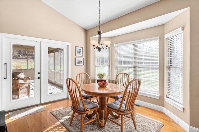 dining space with french doors, an inviting chandelier, vaulted ceiling, and light wood-type flooring