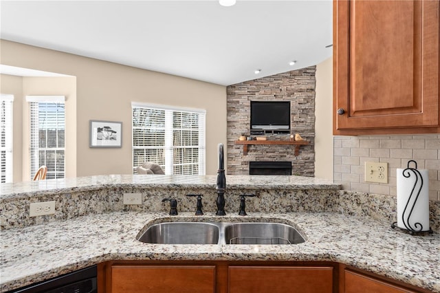 kitchen featuring plenty of natural light, black dishwasher, sink, and light stone countertops