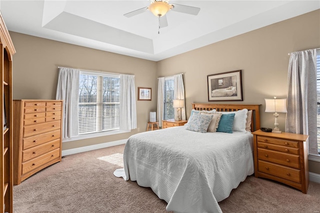 bedroom featuring a tray ceiling, light colored carpet, and ceiling fan