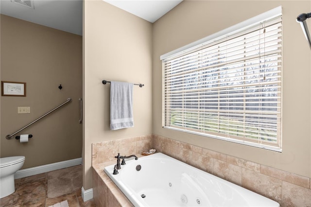 bathroom featuring tiled tub and toilet