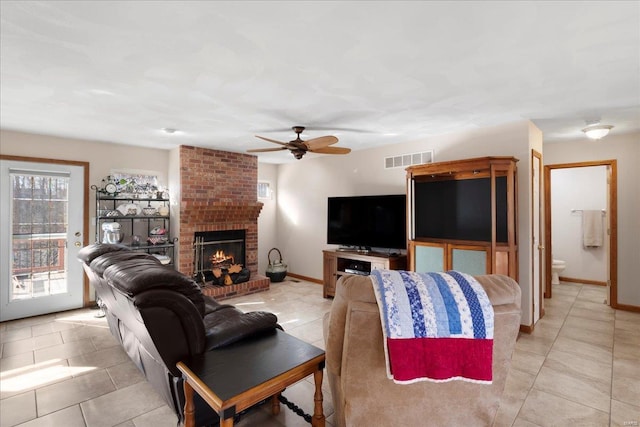 living area featuring visible vents, baseboards, a brick fireplace, and a ceiling fan