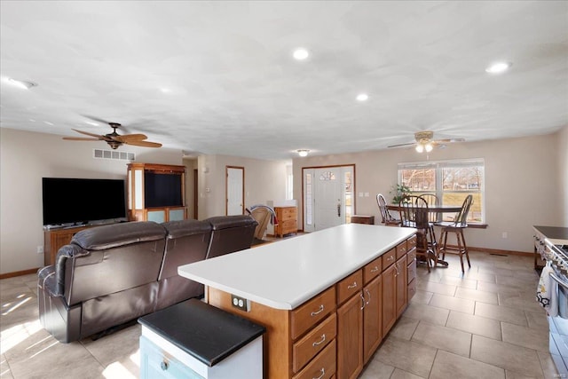 kitchen featuring visible vents, brown cabinets, a center island, and light countertops