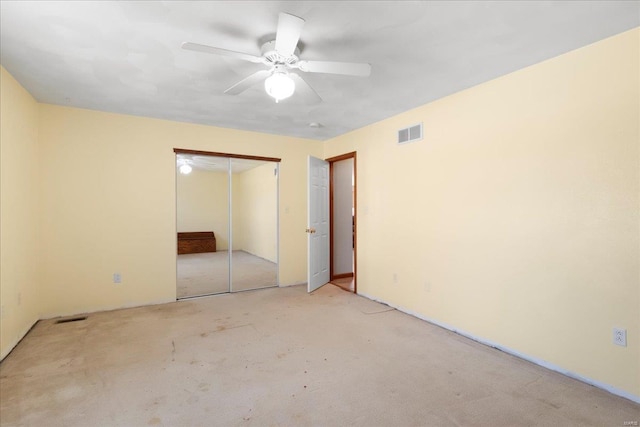 unfurnished bedroom with carpet flooring, a ceiling fan, visible vents, and a closet