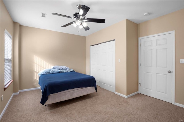 carpeted bedroom with a closet, baseboards, visible vents, and a ceiling fan