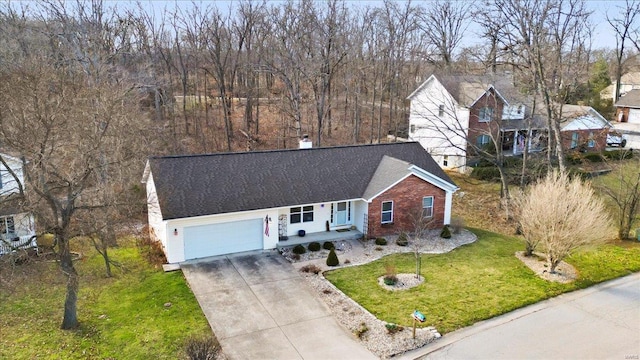 ranch-style home with brick siding, a front lawn, a porch, roof with shingles, and driveway