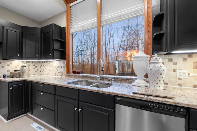 kitchen with dishwasher, sink, and light stone counters