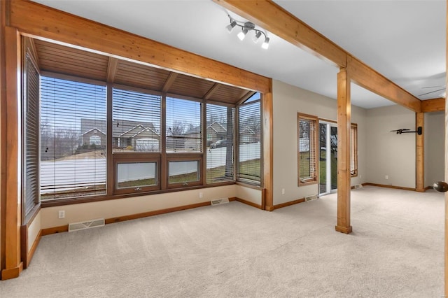 carpeted empty room featuring beam ceiling