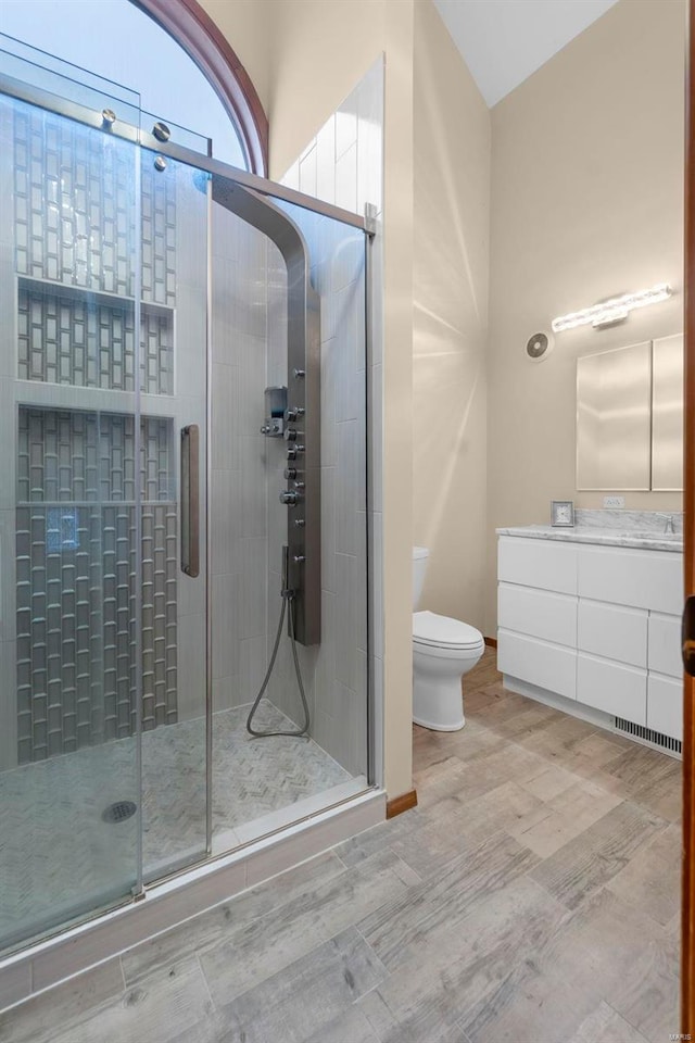 bathroom featuring an enclosed shower, vanity, hardwood / wood-style floors, and toilet