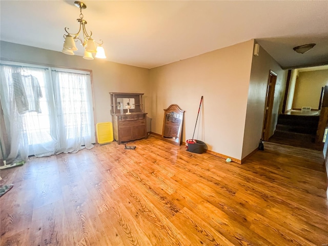 interior space featuring baseboards, light wood finished floors, and an inviting chandelier