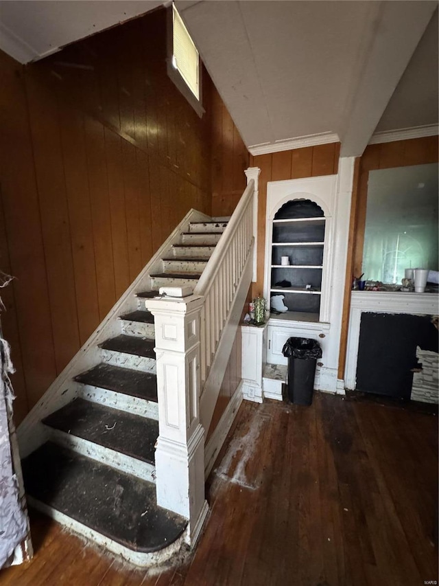 stairway with hardwood / wood-style floors, wooden walls, and built in features