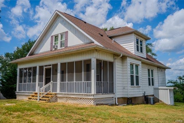 rear view of house with a sunroom, a yard, and cooling unit