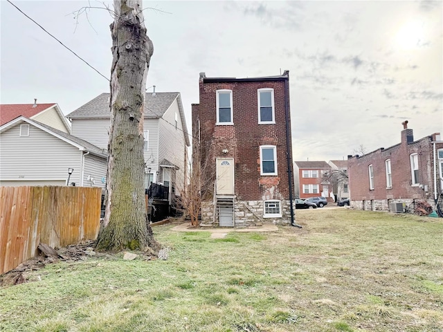 rear view of property with central AC and a lawn