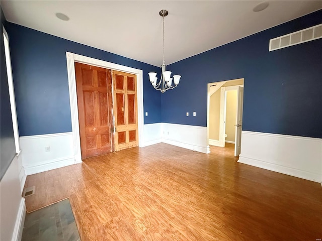 spare room featuring an inviting chandelier and hardwood / wood-style floors