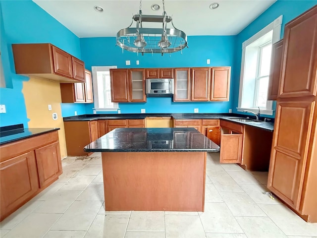 kitchen with sink, light tile patterned floors, dark stone countertops, a kitchen island, and stainless steel appliances