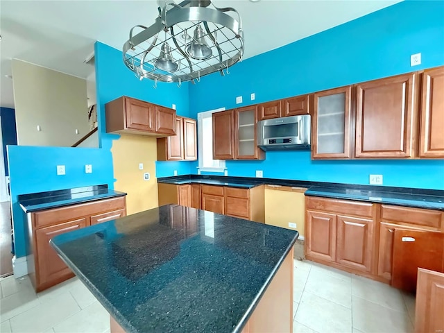 kitchen featuring an inviting chandelier, dark stone counters, a kitchen island, and light tile patterned floors