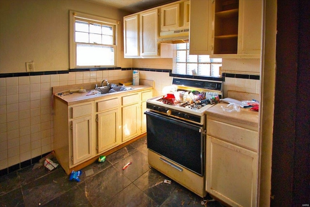 kitchen featuring light brown cabinets, sink, gas range gas stove, and tile walls