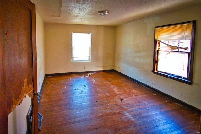 spare room featuring dark hardwood / wood-style floors and a textured ceiling