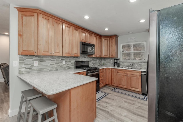 kitchen with sink, a breakfast bar area, light wood-type flooring, kitchen peninsula, and stainless steel appliances