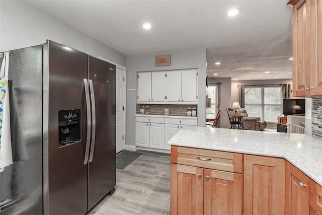 kitchen featuring white cabinets, backsplash, light stone counters, stainless steel fridge with ice dispenser, and light hardwood / wood-style flooring