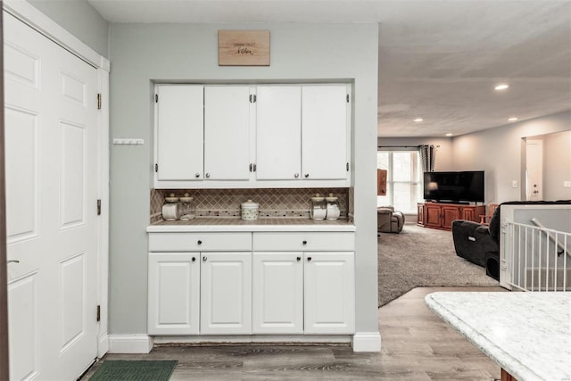 kitchen featuring backsplash, light hardwood / wood-style flooring, and white cabinets