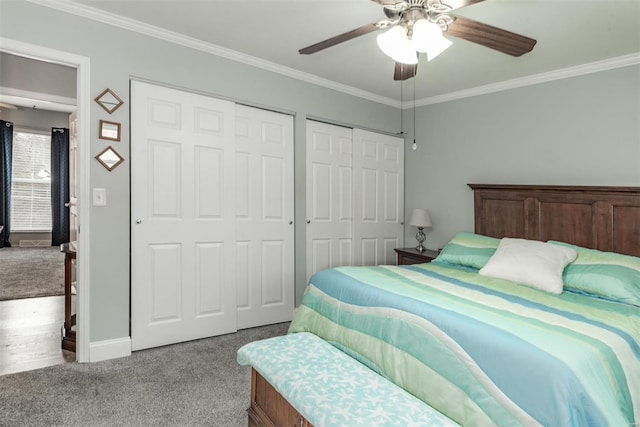 carpeted bedroom featuring crown molding, two closets, and ceiling fan