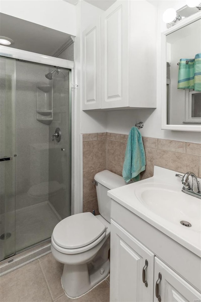 bathroom featuring walk in shower, toilet, tile patterned flooring, and tile walls