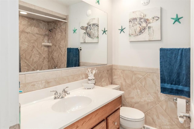 bathroom with vanity, tiled shower, tile walls, and toilet