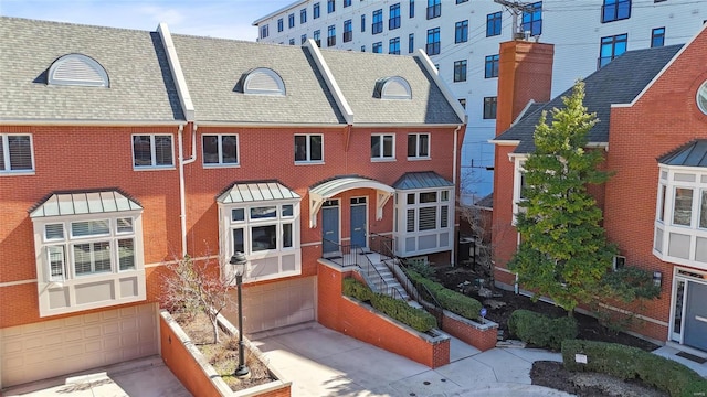 view of property featuring concrete driveway, an attached garage, and brick siding